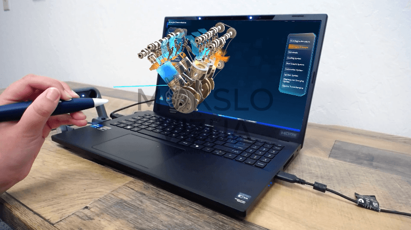 3D Pro mokymų kompiuteris su ekranų projekcija – rodomi trimatės geometrijos objektai ir skraidantys mokymų elementai.