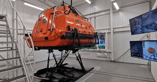 Pilnos misijos treniruoklis A klasės – oranžinės spalvos gelbėjimosi valtis ant judančios bazės su instruktoriaus valdymu.