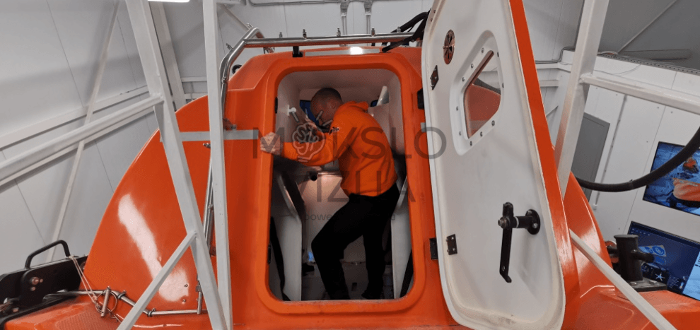 Pilnos misijos gelbėjimosi valties simuliacija su akceleratoriumi, kapitono darbo vieta, patalpų sąlygos ir dinamika, skirta STCW standartams įgyvendinti.