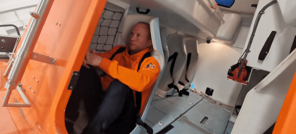 Modernus laivavedybos treniruoklis – valties modelis ant judančios platformos, instruktoriaus pultai ir CCTV stebėjimas simuliacijoje.