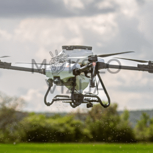 Purškimo dronas skrydyje virš lauko, skirtas augalų priežiūrai ir vienodam purškimo padengimui realiomis sąlygomis.