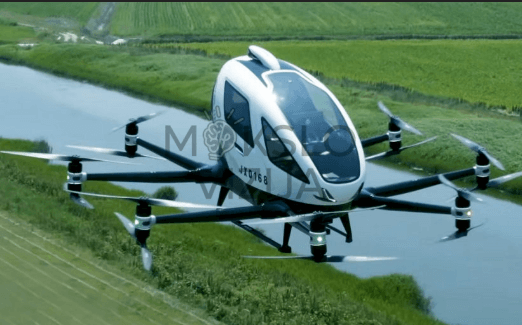 Autonominis elektrinis dvivietis orlaivis skrenda virš kanalo ir laukų, matomas stabilus skrydis ir aplinka.