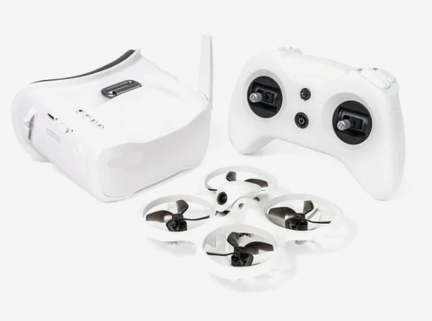 Baltas FPV drono rinkinys su akiniais, nuotolinio valdymo pultu ir kompaktišku dronu su apsaugotais propeleriais.