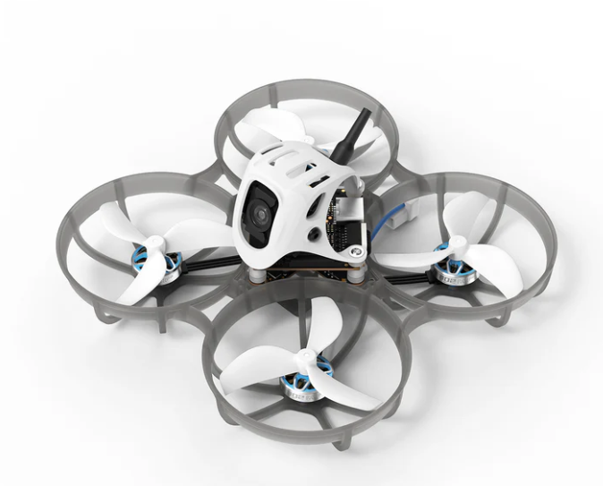 Mini FPV dronas su keturiais propeleriais ir apsauginiais lankais, viršuje matoma kamera ir antena, baltas fonas.