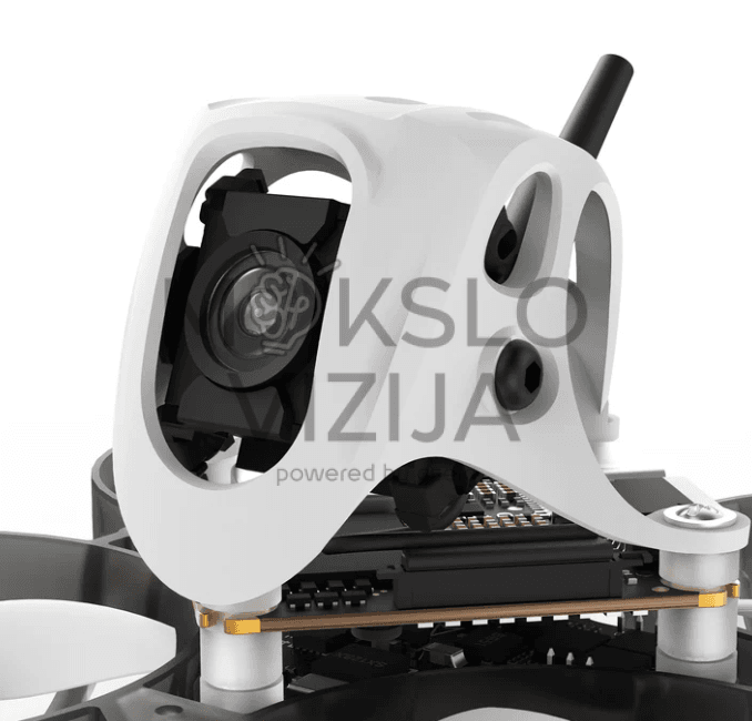 Mini FPV drono kamera ir elektronikos modulis iš arti, matomas korpusas, objektyvas ir antena baltame fone.