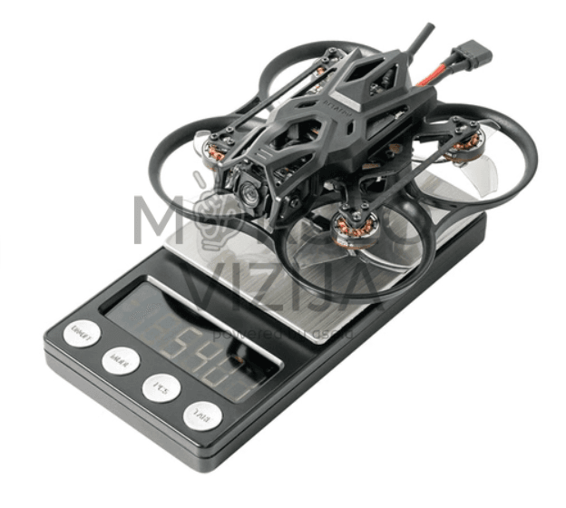 Mini FPV dronas su propelerių apsaugomis padėtas ant elektroninių svarstyklių, matomas drono svoris ir konstrukcija.