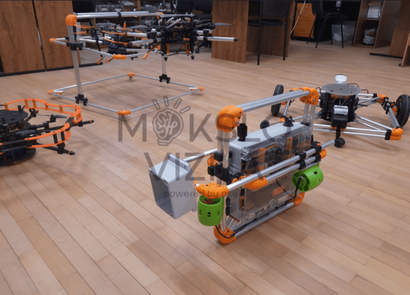 Povandeninis robotas su tvirtu rėmu ir moduliais testuojamas patalpoje ant grindų, matoma mokomoji laboratorinė aplinka.