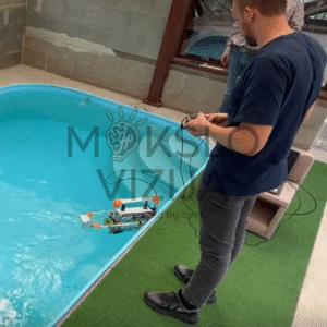 Operatorius valdo povandeninį robotą baseine, matomas kabelinis ryšys ir roboto judėjimas vandenyje.