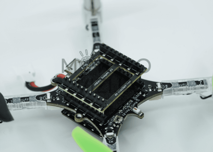 Mini drono elektronikos plokštė ir jungtys iš arti, matomos detalės, baterija ir konstrukcijos elementai.