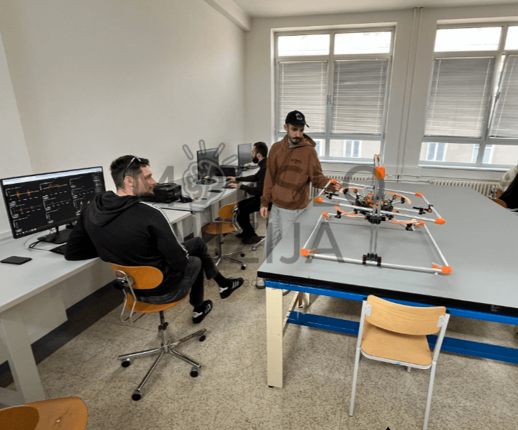 DTL QUAD KIT LITE dronas bandymų stende laboratorijoje su valdymo pultu ir kompiuterio ekranu
