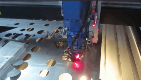 lazerinio pjovimo galvutė pjauna metalinį ruošinį su ryškiu lazerio spinduliu darbo zonoje