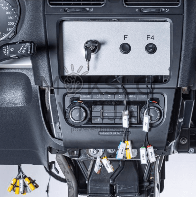 Automobilio centrinės konsolės modulis su pažymėtomis diagnostikos jungtimis ir laidais komforto sistemų mokymui.