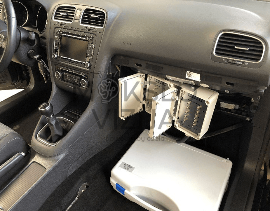 Golf mokymo automobilio salono vaizdas su atvira prietaisų skydelio zona, ištraukiamais valdymo blokais, diagnostikos moduliais ir centrine konsole.