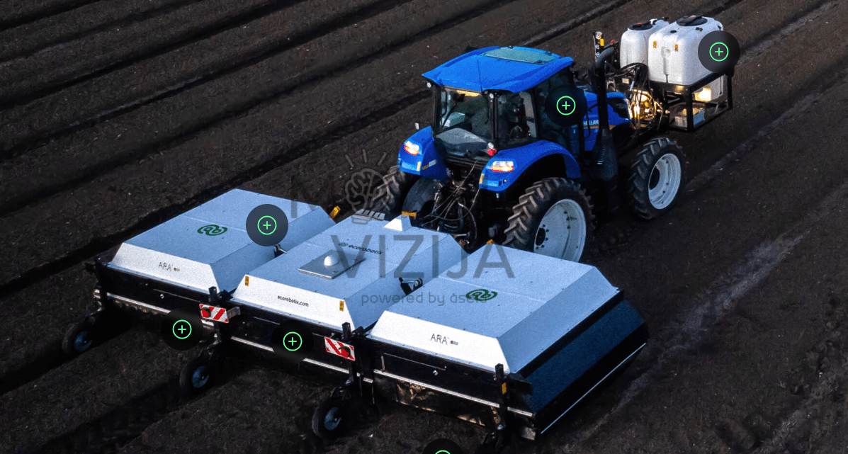 Mėlynas traktorius su tempiama precizinio purškimo sistema dirba vagotame lauke, matomas galinis purškimo modulis ir priekinė talpa.