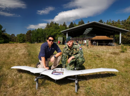 DeltaQuad Evo fiksuoto sparno dronas ant žemės su operatoriais, skirtas profesionalioms kartografavimo ir stebėjimo misijoms.