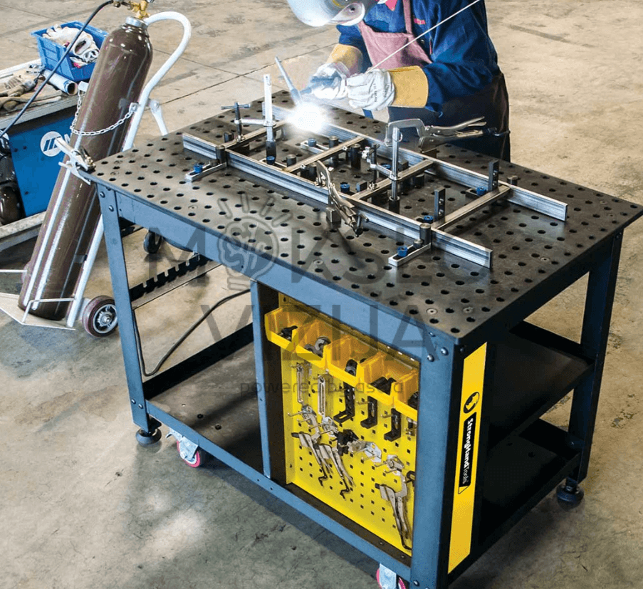 Mokinys atlieka suvirinimo pratimą ant perforuoto suvirinimo stalo su detalių fiksavimo sistema profesinio rengimo centre