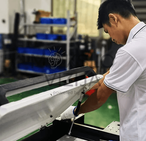 Operatorius atlieka lazerinio suvirinimo darbus gamybinėje aplinkoje su rankiniu įrenginiu.