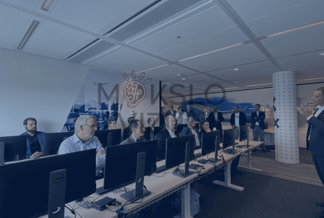 Kibernetinio saugumo mokymų auditorija su kompiuterinėmis darbo vietomis, kur dalyviai realiuoju laiku mokosi reaguoti į kibernetines grėsmes.