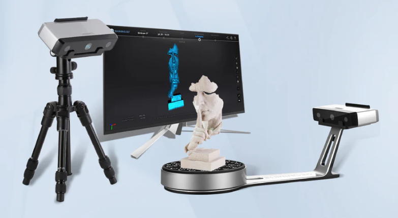 Stalinis 3D skeneris su sukamu stalu, monitoriumi ir trikojų sistema, šalia pavaizduotas nuskenuotas objektas.