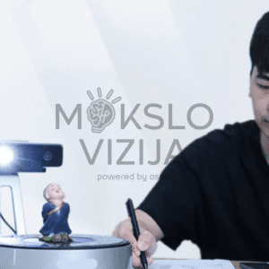 Stalinis 3D skeneris su ryškiu apšvietimu skenuoja objektą ant sukamo stalo, šalia dirba operatorius su kompiuteriu.