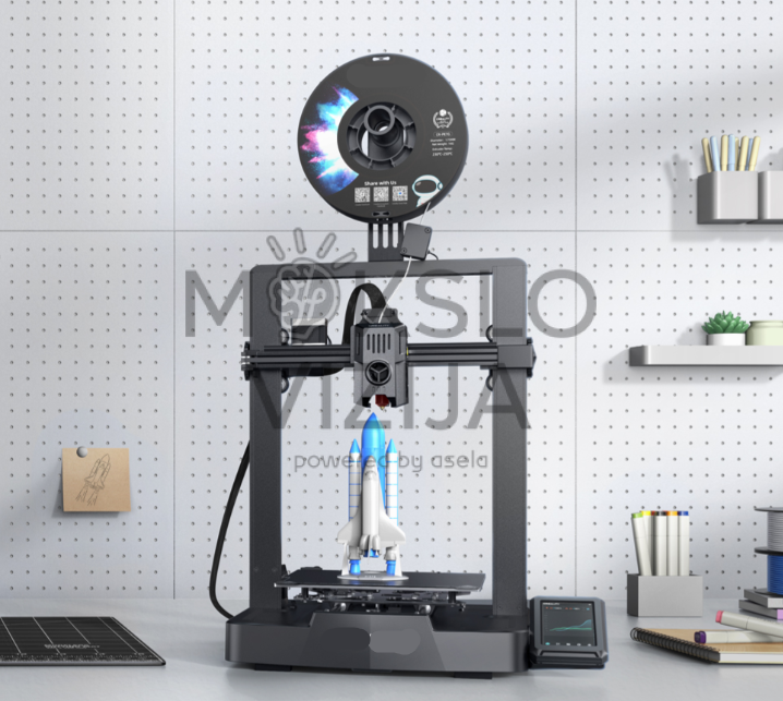 Creality Ender-3 V3 KE 3D spausdintuvas ant darbo stalo su gijos rite viršuje ir spausdinamu raketos modeliu, šalia matomas valdymo ekranas.