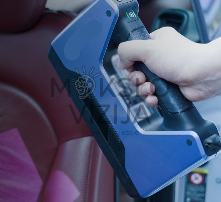 Rankoje laikomas mėlynos spalvos rankinis 3D skeneris, naudojamas skenuoti automobilio salono paviršių.