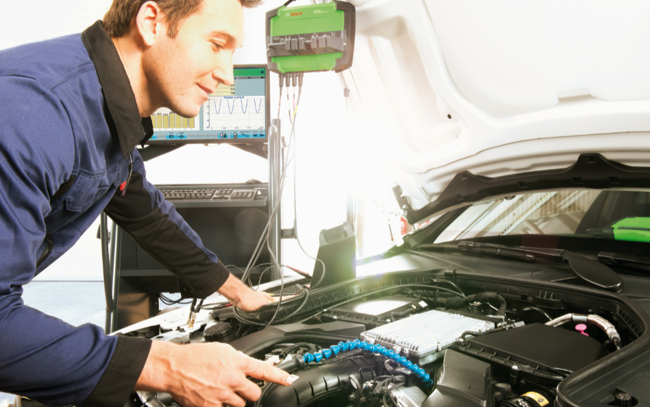 Mechanikas atlieka automobilio variklio diagnostiką naudojant Bosch FSA 740 sistemų analizatorių su prijungtais matavimo laidais.