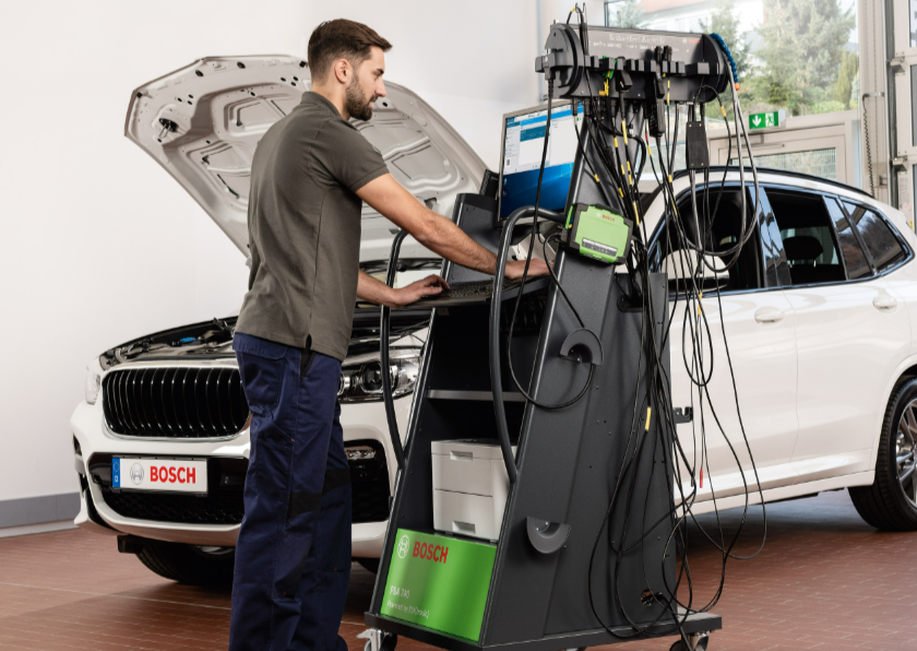 Autoserviso mechanikas naudoja Bosch FSA 740 su KTS 560 diagnostikos stotį prie automobilio su atidarytu variklio dangčiu.