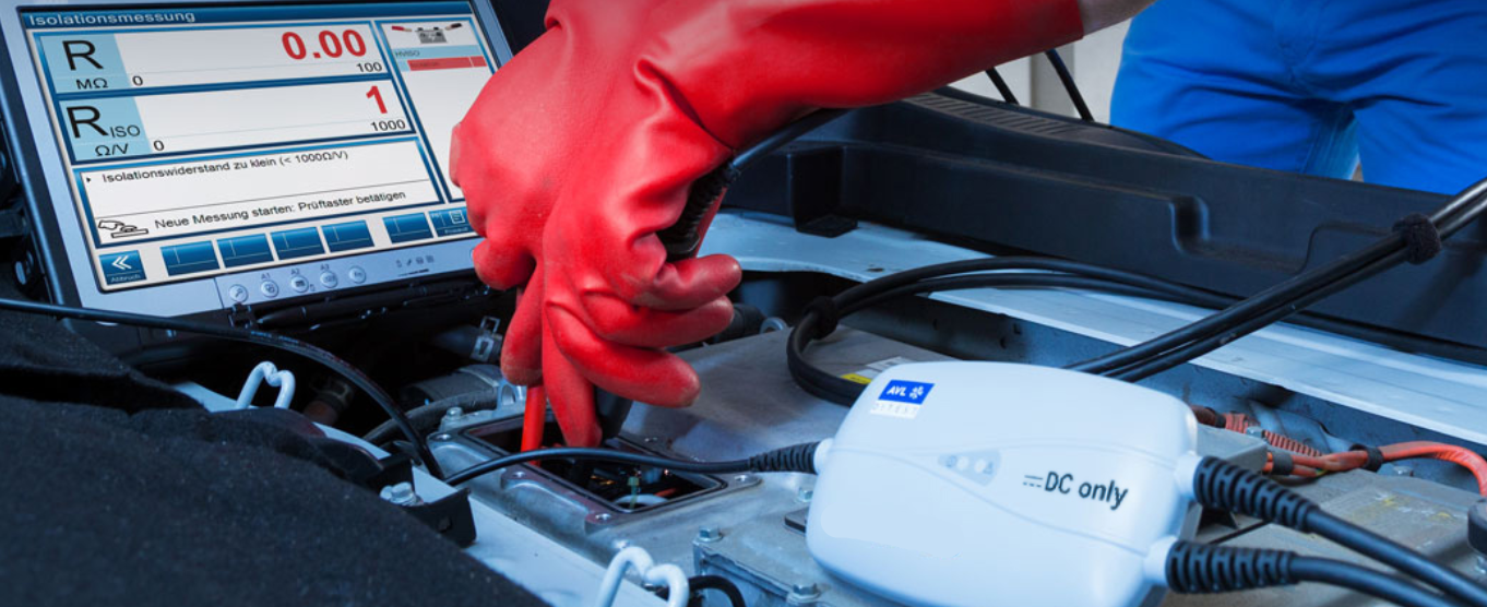 Aukštos įtampos izoliacijos matavimas elektrinio automobilio baterijos sistemoje naudojant diagnostikos prietaisą ir apsaugines pirštines.
