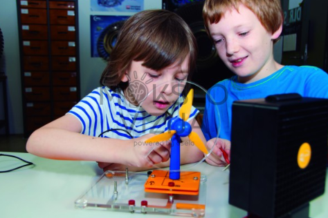 Du vaikai atlieka vėjo energijos eksperimentą su mokomąja vėjo turbina ir laboratorine platforma.