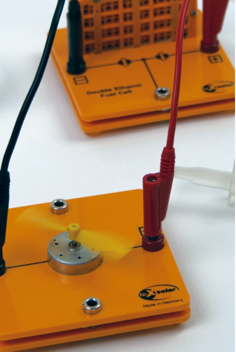 Dvi studentės laboratorijoje atlieka vandenilio technologijų eksperimentą su matavimo prietaisais ir stikline įranga.
