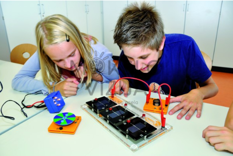 Du mokiniai atlieka saulės energijos eksperimentą su saulės moduliais, laidais ir matavimo įranga ant laboratorinio stalo.