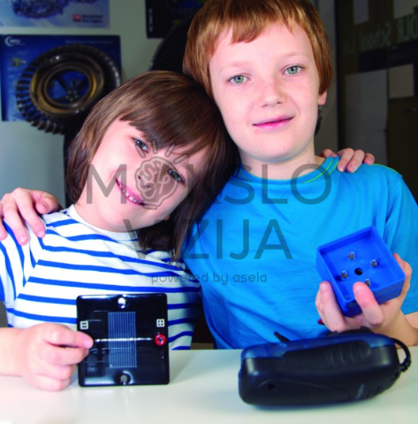 Du vaikai laiko saulės modulį ir mokymo komponentą atsinaujinančios energijos eksperimento metu.