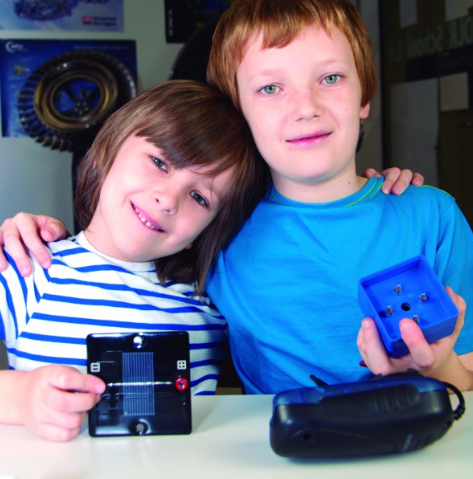 Du vaikai laiko saulės modulį ir mokymo komponentą atsinaujinančios energijos eksperimento metu.