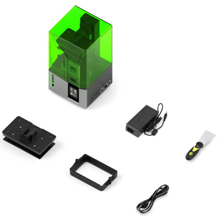 Resin 3D spausdintuvas su žaliu gaubtu ir šalia išdėliotu maitinimo adapteriu, mentele, platforma ir papildomais komponentais ant balto fono