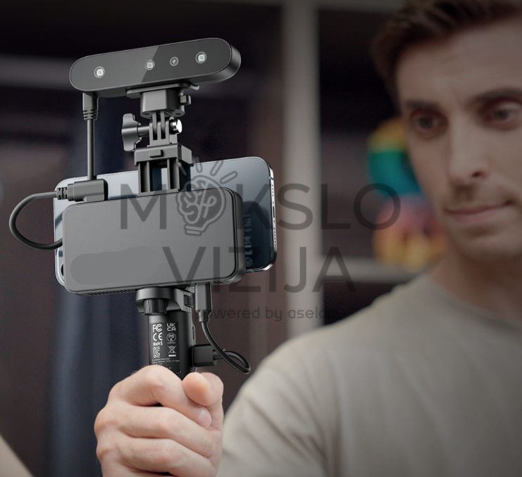 Rankinis 3D skeneris pritvirtintas prie išmaniojo telefono, laikomas rankoje su stabilizavimo rankena, skirtas mobiliam 3D skenavimui.