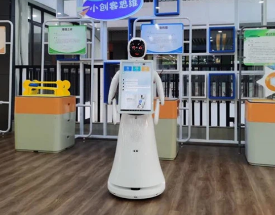 Mobilus dirbtinio intelekto informacinis robotas su ekranu, naudojamas švietimo ar ekspozicinėje aplinkoje lankytojų navigacijai.