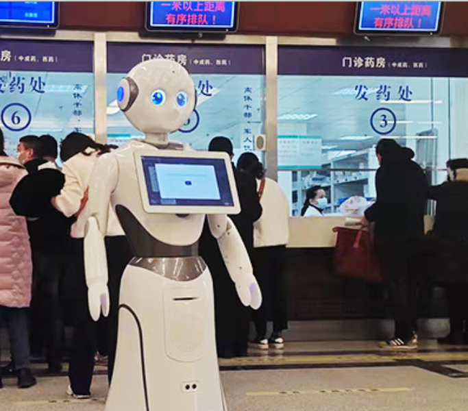 Humanoidinis AI serviso robotas su ekranu ligoninės registratūroje, skirtas pacientų konsultavimui ir informacijos pateikimui.