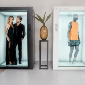 Dvi kompaktiškos holografinės vitrinos – juoda ir balta – rodo 3D žmogaus modelius bei produktų vizualizacijas modernioje interjero aplinkoje.