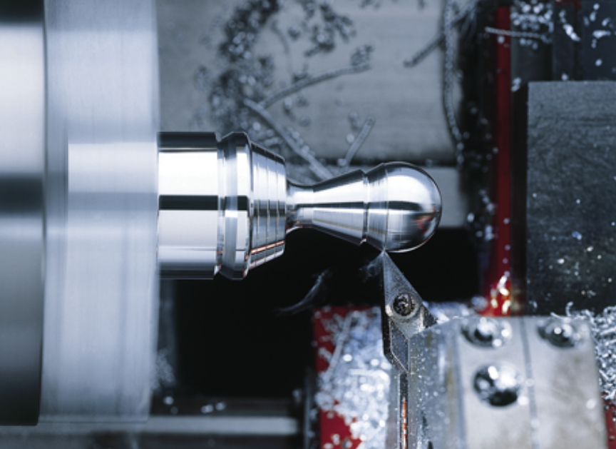 CNC tekinimo procesas, kai pjovimo įrankis apdirba metalinį ruošinį ir formuoja detalės paviršių CNC tekinimo staklėse.