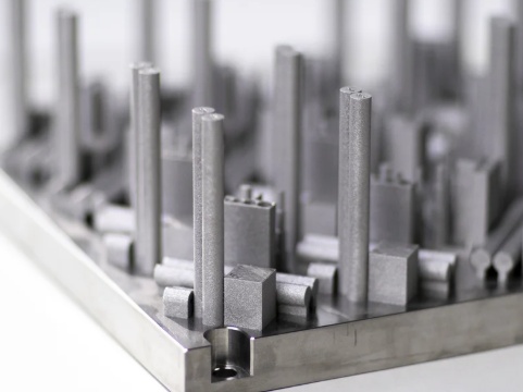 Metalo 3D spausdinimo būdu pagamintos sudėtingos geometrijos metalinės detalės ant spausdinimo platformos.