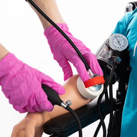 Medicinos studentas matuoja kraujospūdį ant rankos treniruoklio prijungto prie paciento simuliatoriaus
