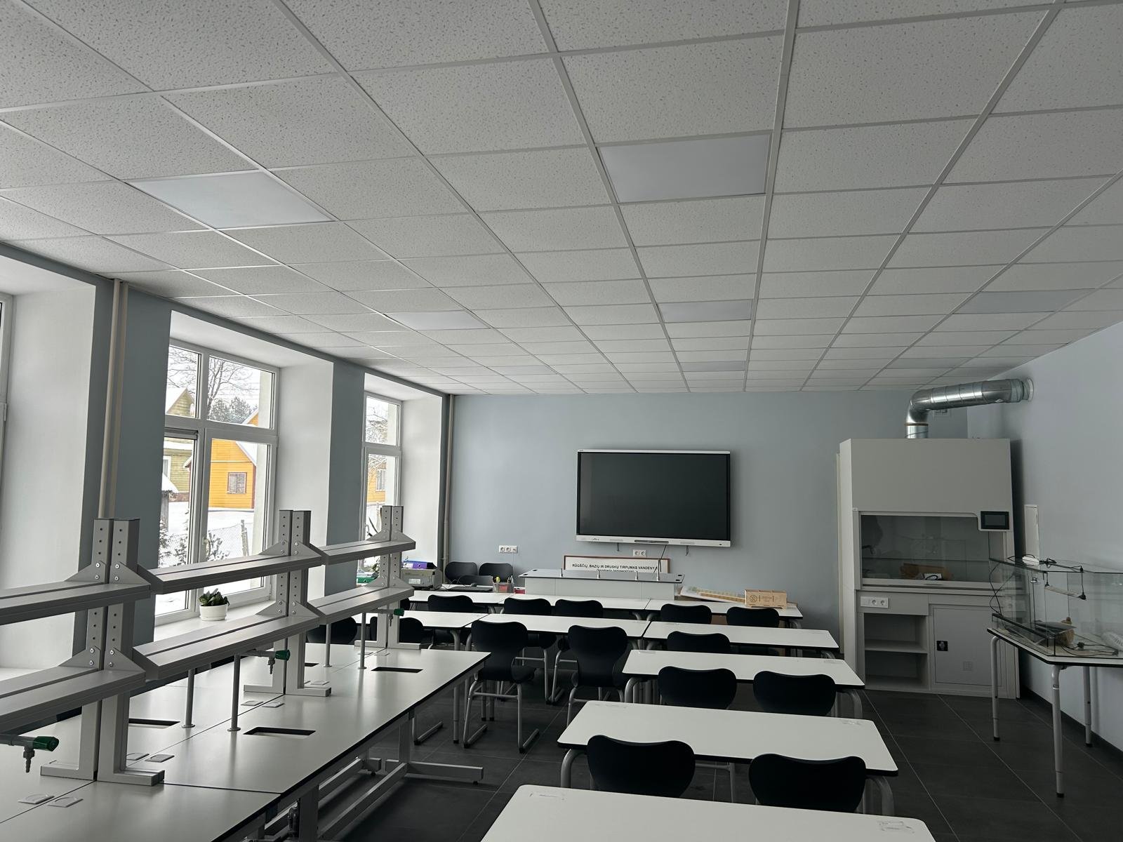 Moderni fizikos laboratorija su demonstraciniu stalu, traukos spinta ir mokinių darbo vietomis.