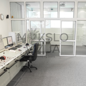 Laivo mašinų skyriaus simuliatoriaus valdymo centras su operatoriaus pultais, monitoriais ir mokymo darbo vietomis.